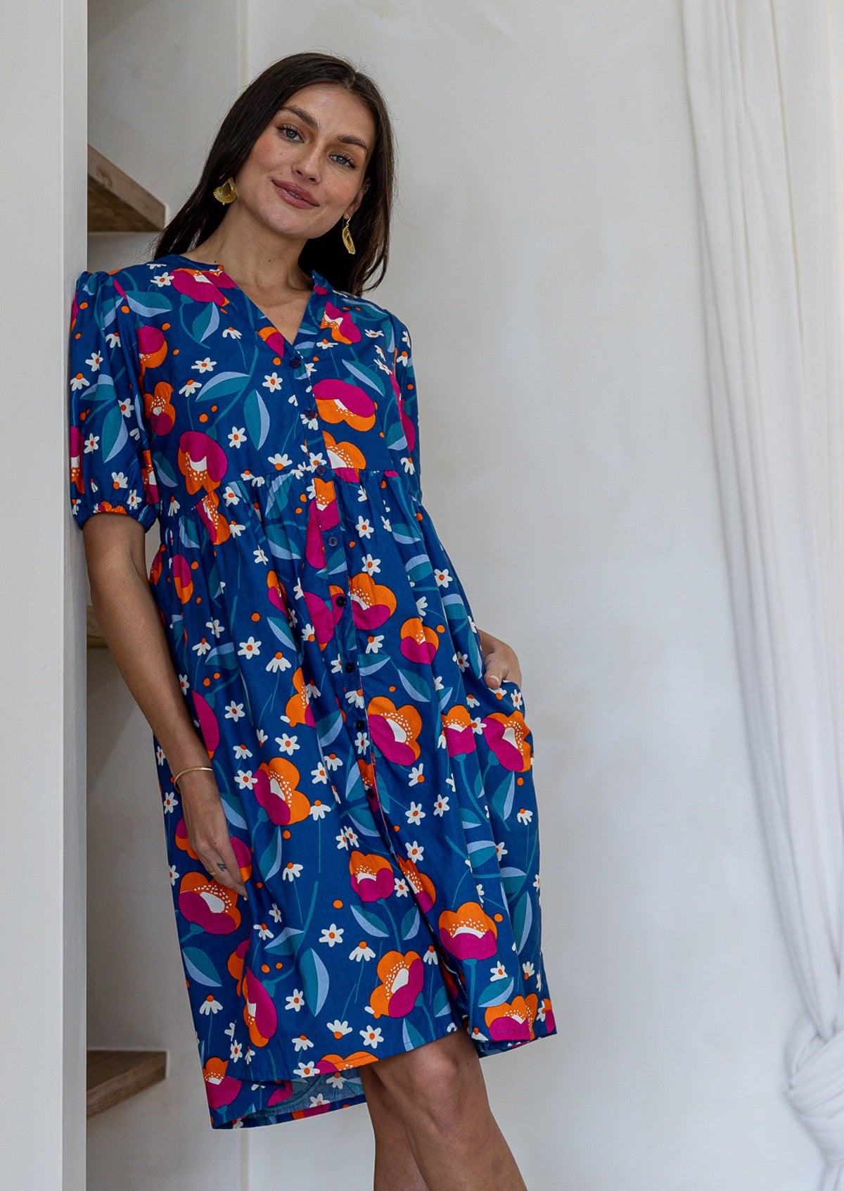 A woman modeling a short-sleeve V-neck 100% cotton dress in royal blue based floral print.