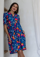 A woman modeling a short-sleeve V-neck 100% cotton dress in royal blue based floral print.