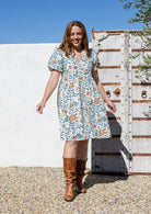 Woman standing wearing a 100% cotton dress with white based floral print