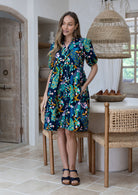 Woman wearing a knee length relaxed fit button through 100% cotton dress with elbow length sleeves