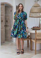 Woman wearing navy blue based multicolour ifloral print 100% cotton dress with, relaxed fit, empire waistline and elasticated elbow length sleeves