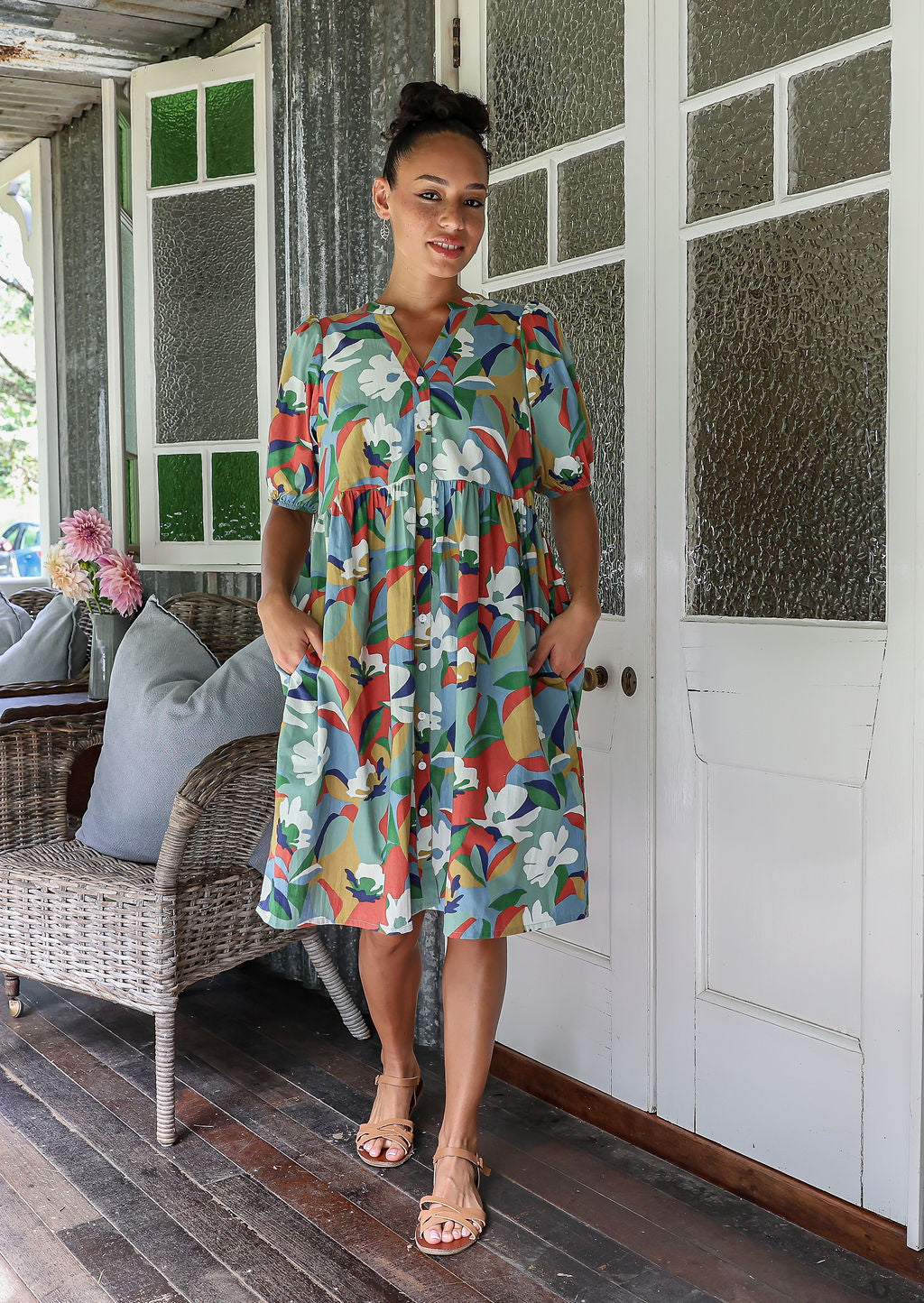 Woman wearing colourful floral print 100% cotton dress with, relaxed fit, empire waistline and elasticated elbow length sleeves