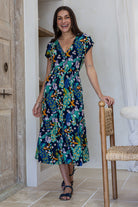 Woman standing in midi length rayon dress button through dress with V-neckline and elasticated waistband