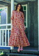 Woman wearing a 100% cotton tiered maxi dress in cream based floral print