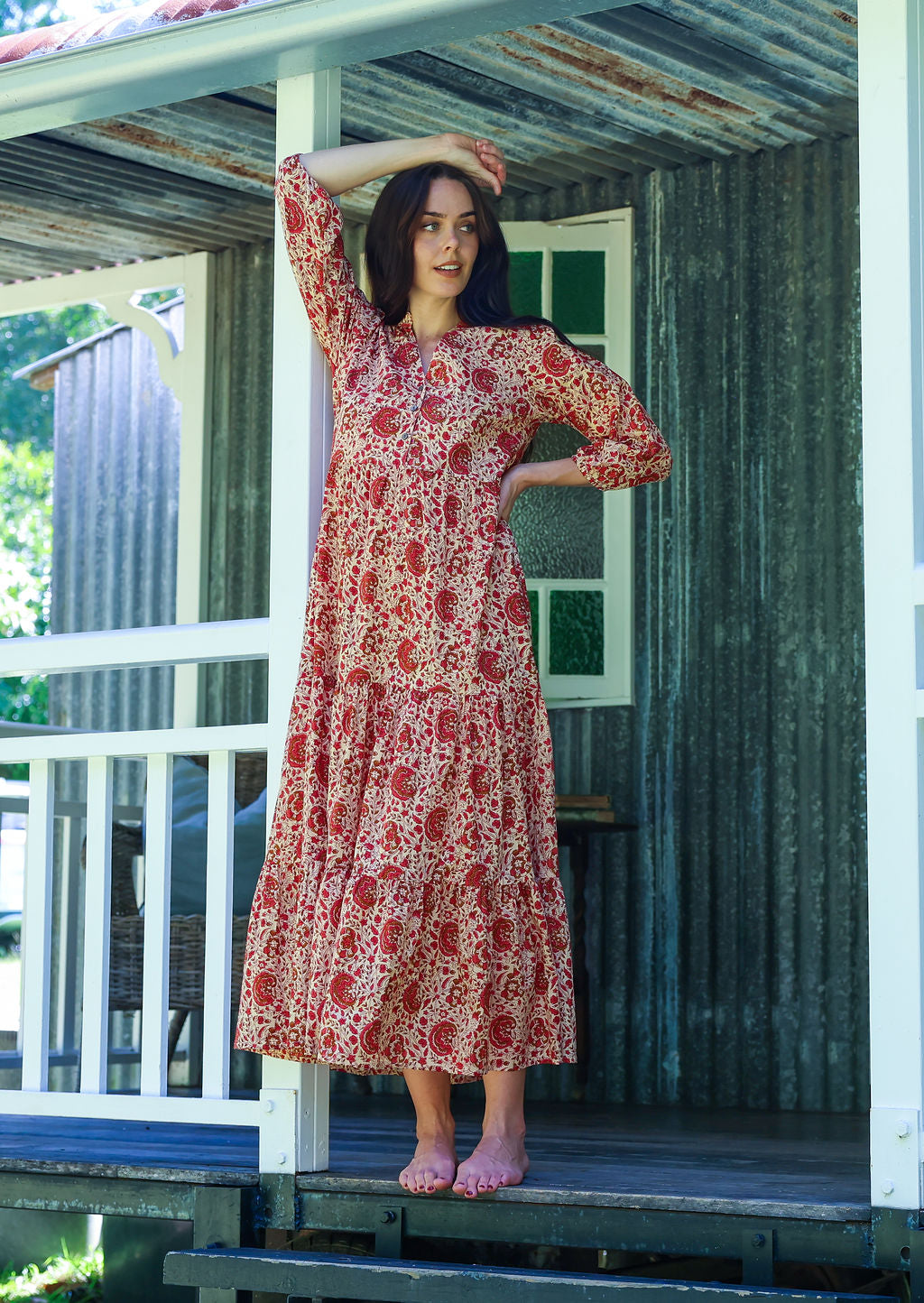 Woman poses floral cotton maxi dress with buttoned bodice, 3/4 sleeves and flowy three tiered maxi skirt