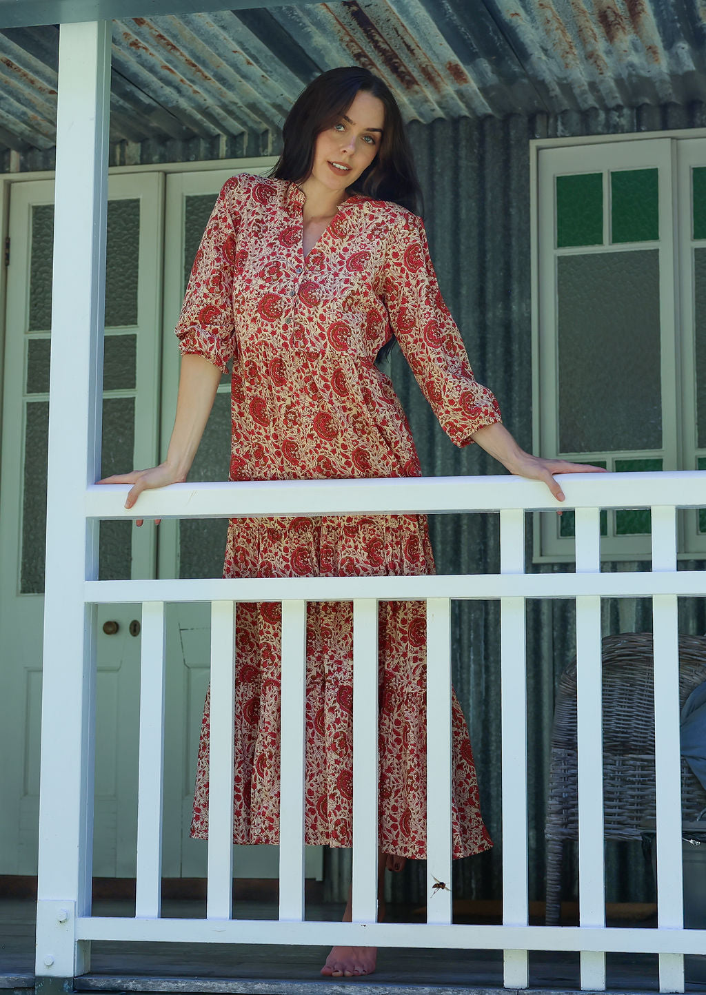 Woman in a floral dress standing on a porch