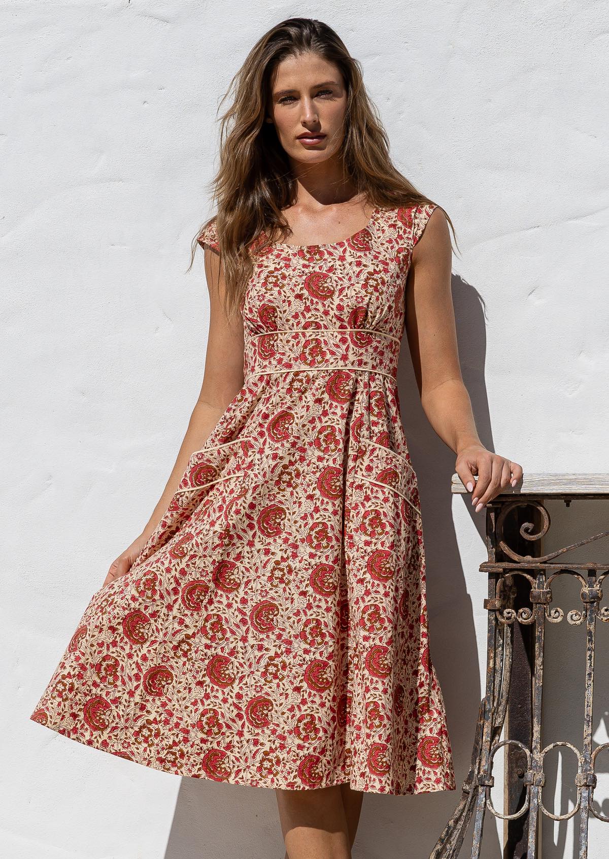 Model flaunting a knee length 100% cotton dress in cream based floral print with scoop neck, pockets and cap sleeves