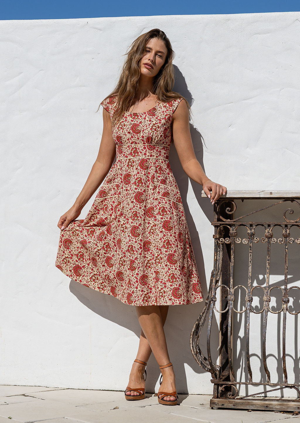 Model in knee length, cream based floral print 100 percent cotton scoop neck retro style dress.