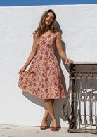 Model in knee length, cream based floral print 100 percent cotton scoop neck retro style dress.