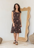 Model in knee length, black 100 percent cotton scoop neck Indian traditional style print dress with pockets and cap sleeves 