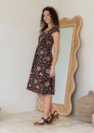 Model in knee length, black 100 percent cotton scoop neck dress with pockets and cap sleeves 