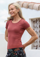Woman wearing a terracotta fitted t-shirt with short sleeves and a deep round neckline