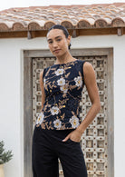 Woman wearing a black sleeveless top with floral pattern paired with plain black pants
