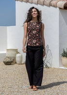 Model poses in a vintage style sleeveless cotton top with plain black trim around the arms and a side zipper 