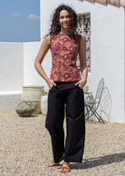 woman in floral sleeveless, tailored top and black pants standing in an outdoor setting