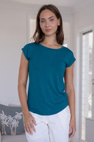 Woman wearing a teal stretch rayon jersey t-shirt and white pants