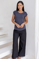 Woman wearing a 100% rayon dark grey shell top and black pants standing on a white staircase.