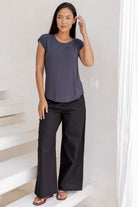 Woman wearing a 100% rayon dark grey top and black pants standing in a room with white walls and a staircase.