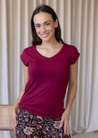 Woman wearing a maroon rayon jersey t-shirt with a V-neckline and short sleeves