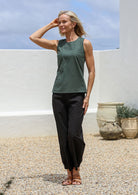 Woman posing in sleeveless relaxed fit cotton top in jungle green with round neckline and side bust darts 