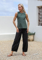 Woman wearing a 100% cotton jungle green sleeveless top with round neckline, paired with black cotton pants