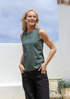 Woman wearing a relaxed fit 100% cotton green sleeveless top and black pants standing outdoors