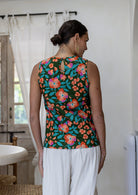 Woman standing backwards wears 100% cotton floral top, sleeveless design. 