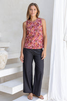 Woman standing in front of white wall wears 100% cotton sleeveless floral print top with keyhole button closure at the back