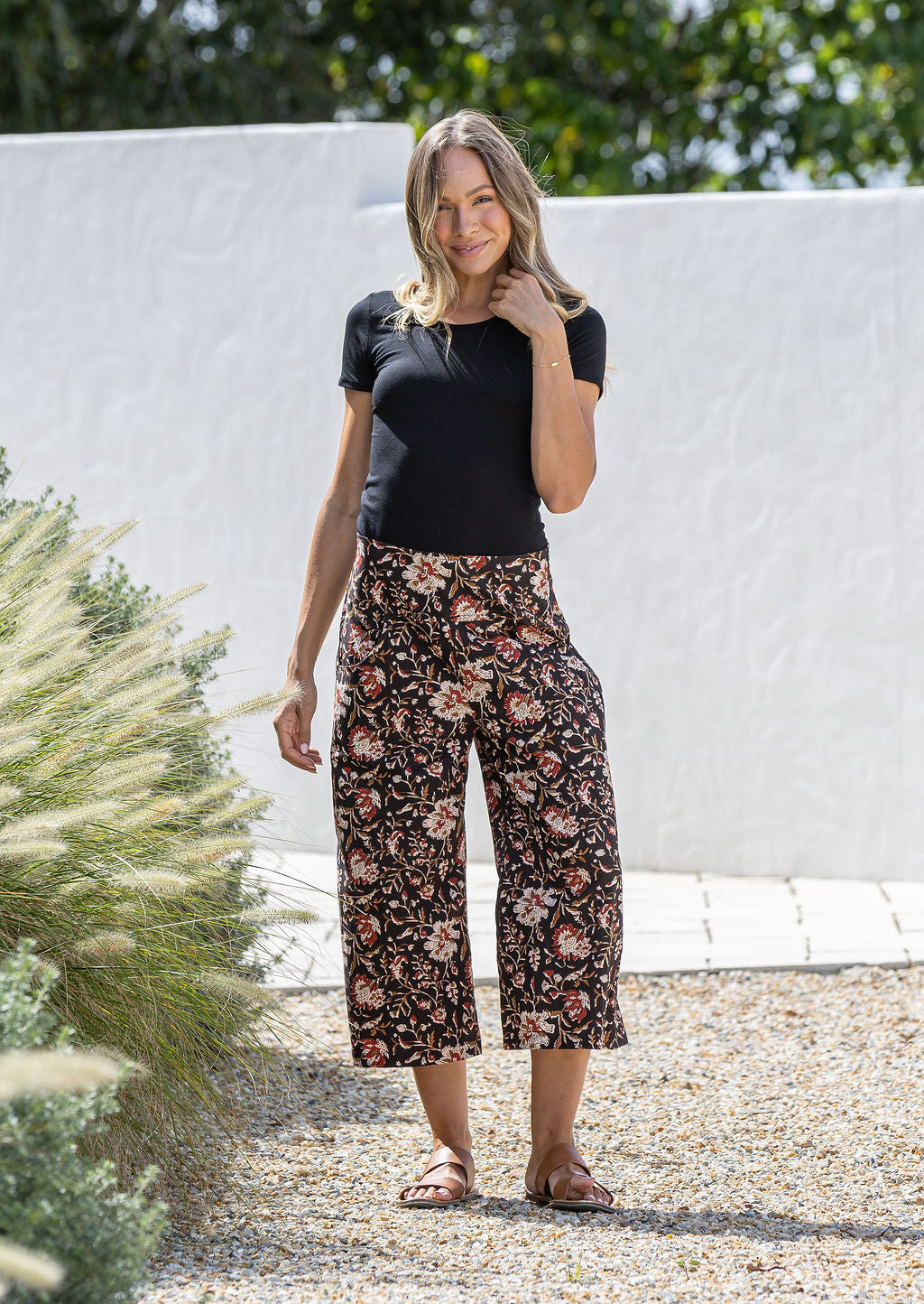 Woman wearing a black basic rayon top and black based floral print wide leg 3/4 cotton pants with side zipper and pockets