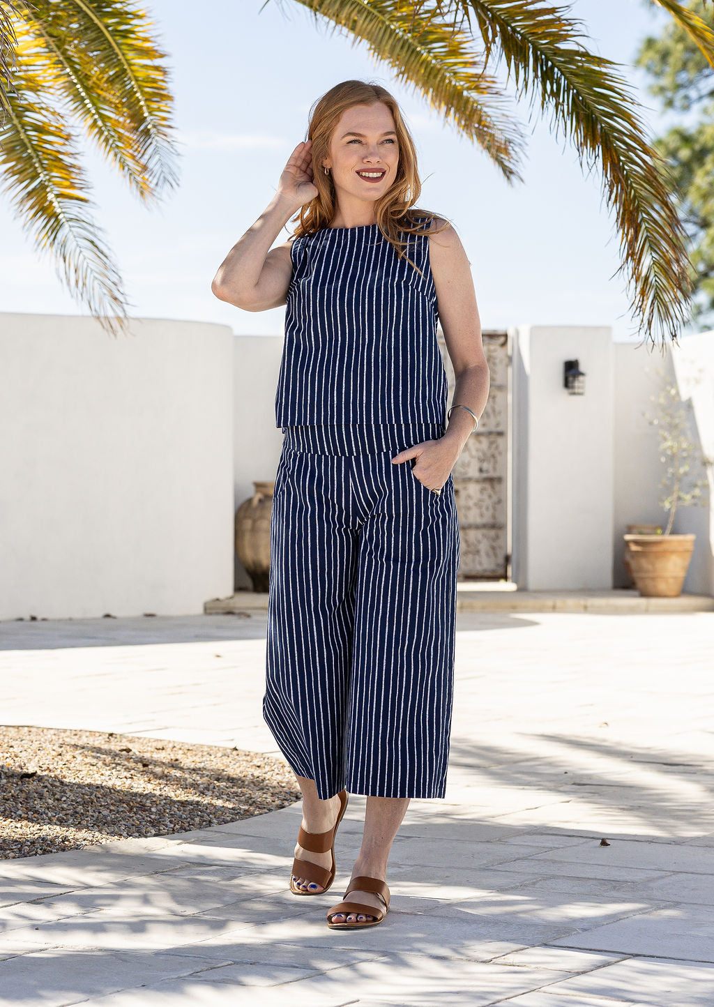 Model stands wearing a sleeveless floral cotton boxy top paired with the same print cotton pants.