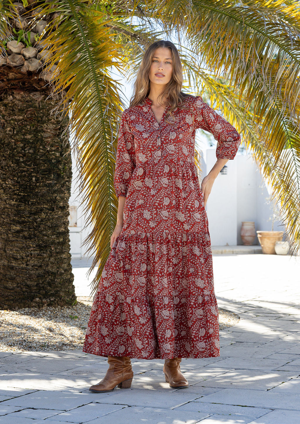 Woman poses floral cotton maxi dress with buttoned bodice, 3/4 sleeves and flowy three tiered maxi skirt
