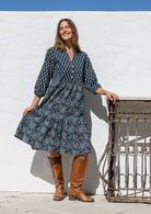 Woman flaunting a cotton tiered over the knee dress with 3/4 sleeves, buttoned bodice and V-neckline