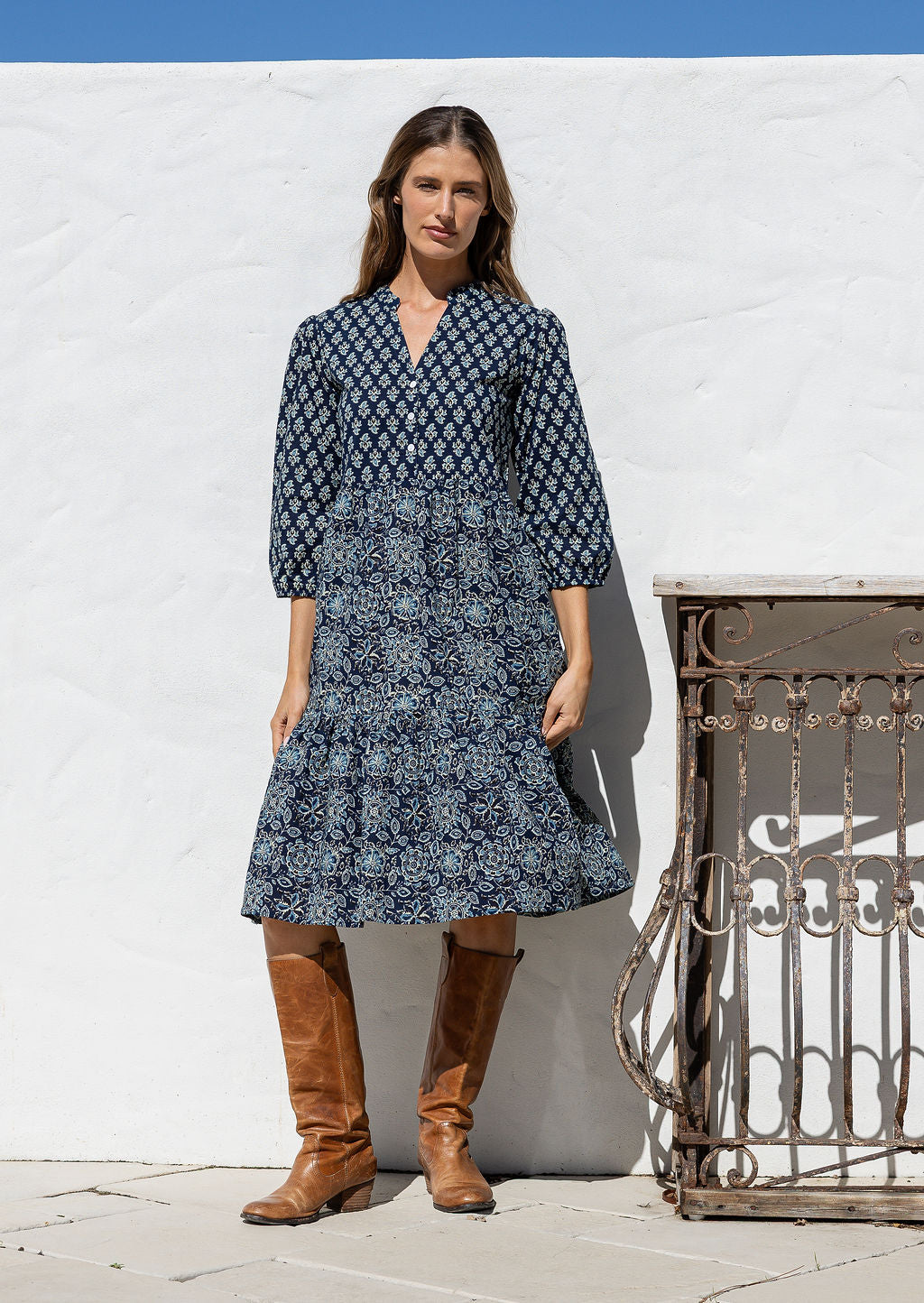 Woman wearing a 100% cotton tiered over the knee dress with 3/4 sleeves, buttoned bodice and V-neckline
