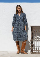 Model stands on in cotton over the knee length relaxed fit dress with 3/4 sleeves, paired with brown boots.