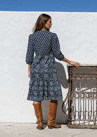 Model stands backwards on in cotton over the knee length relaxed fit dress with 3/4 sleeves, paired with brown boots. 