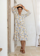 Woman wearing a 100% cotton tiered over the knee dress with 3/4 sleeves, buttoned bodice and V-neckline