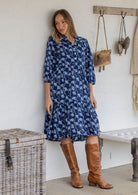 Woman poses in cotton tiered over the knee dress with 3/4 sleeves, buttoned bodice and V-neckline