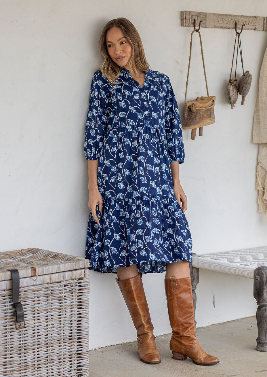 Woman poses in cotton tiered over the knee dress with 3/4 sleeves, buttoned bodice and V-neckline