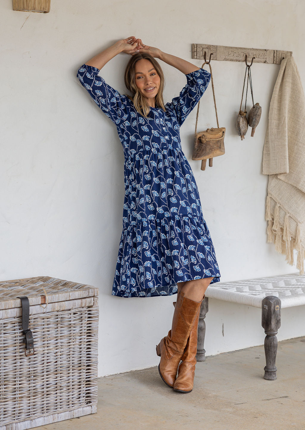 Woman wearing a 100% cotton tiered over the knee dress with 3/4 sleeves, buttoned bodice and V-neckline