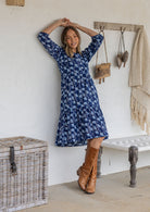 Woman wearing a 100% cotton tiered over the knee dress with 3/4 sleeves, buttoned bodice and V-neckline
