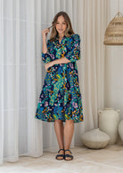 Woman wearing a 100% cotton tiered over the knee dress with 3/4 sleeves, buttoned bodice and V-neckline