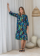 Woman wearing a cotton tiered over the knee dress with 3/4 sleeves, buttoned bodice and V-neckline