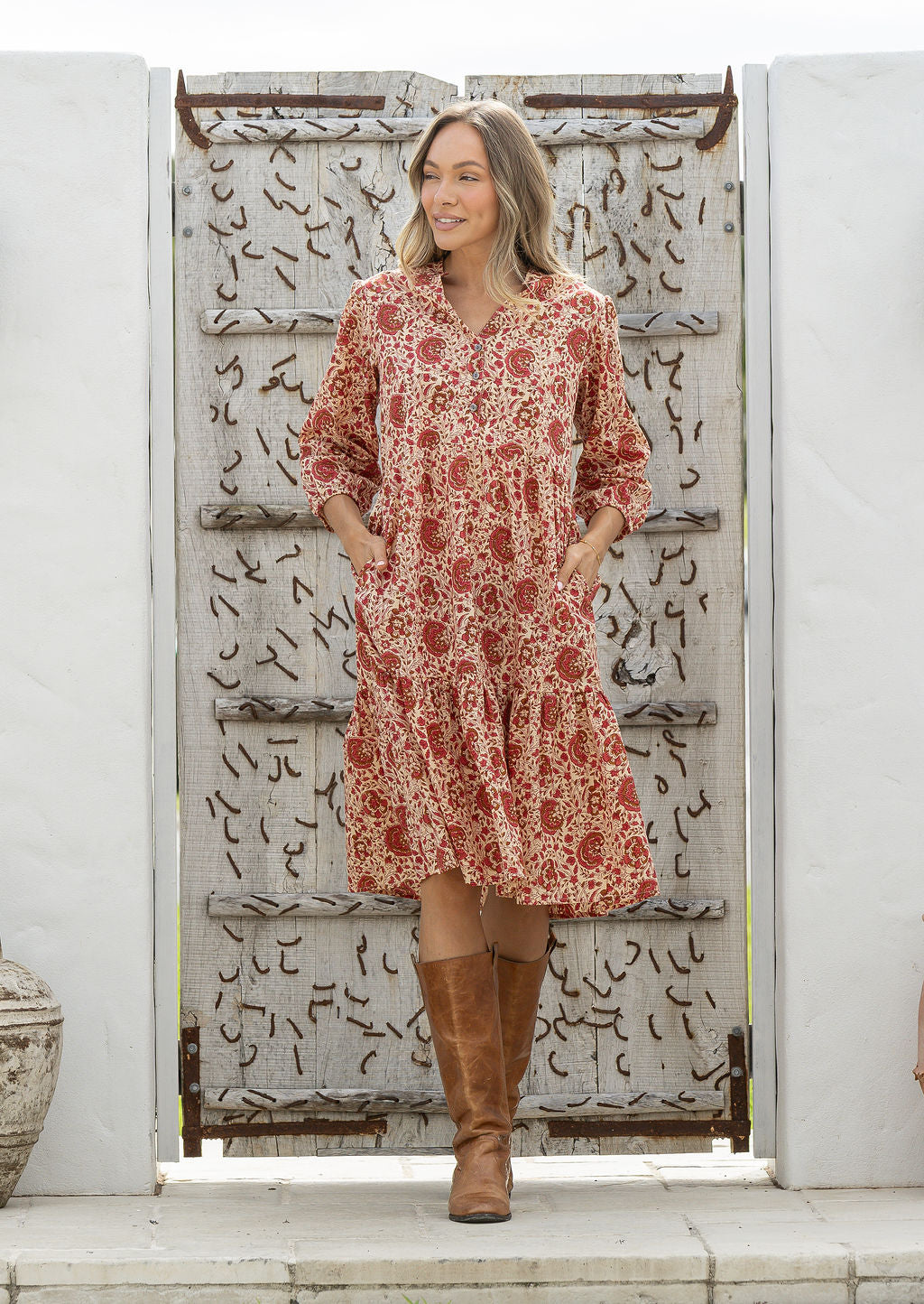 Woman poses in cotton tiered over the knee dress with 3/4 sleeves, buttoned bodice and V-neckline