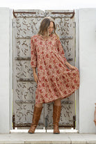 Woman flaunting cotton tiered dress in cream based floral print, with 3/4 sleeves, buttoned bodice and V-necklin