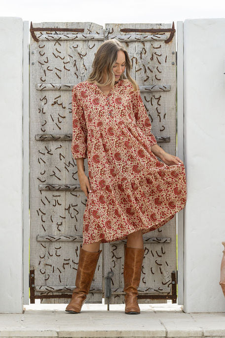 Woman flaunting cotton tiered dress in cream based floral print, with 3/4 sleeves, buttoned bodice and V-necklin