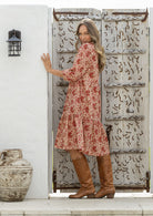 Model stands side on in cotton over the knee length relaxed fit dress with 3/4 sleeves, paired with tan sandals 