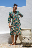 Woman wearing a 100% cotton tiered over the knee dress with 3/4 sleeves, buttoned bodice and V-neckline