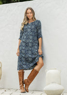 Woman wearing a 100% cotton navy blue based floral dress with sleeves and pockets