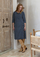 Woman wearing a relaxed fit below knee length cotton dress with 3/4 sleeves, pockets and round neckline.