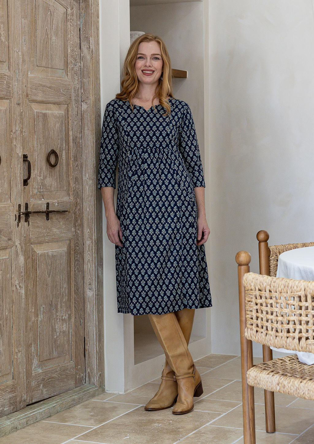 Woman wearing a 100% cotton navy blue based floral dress with sleeves and pockets